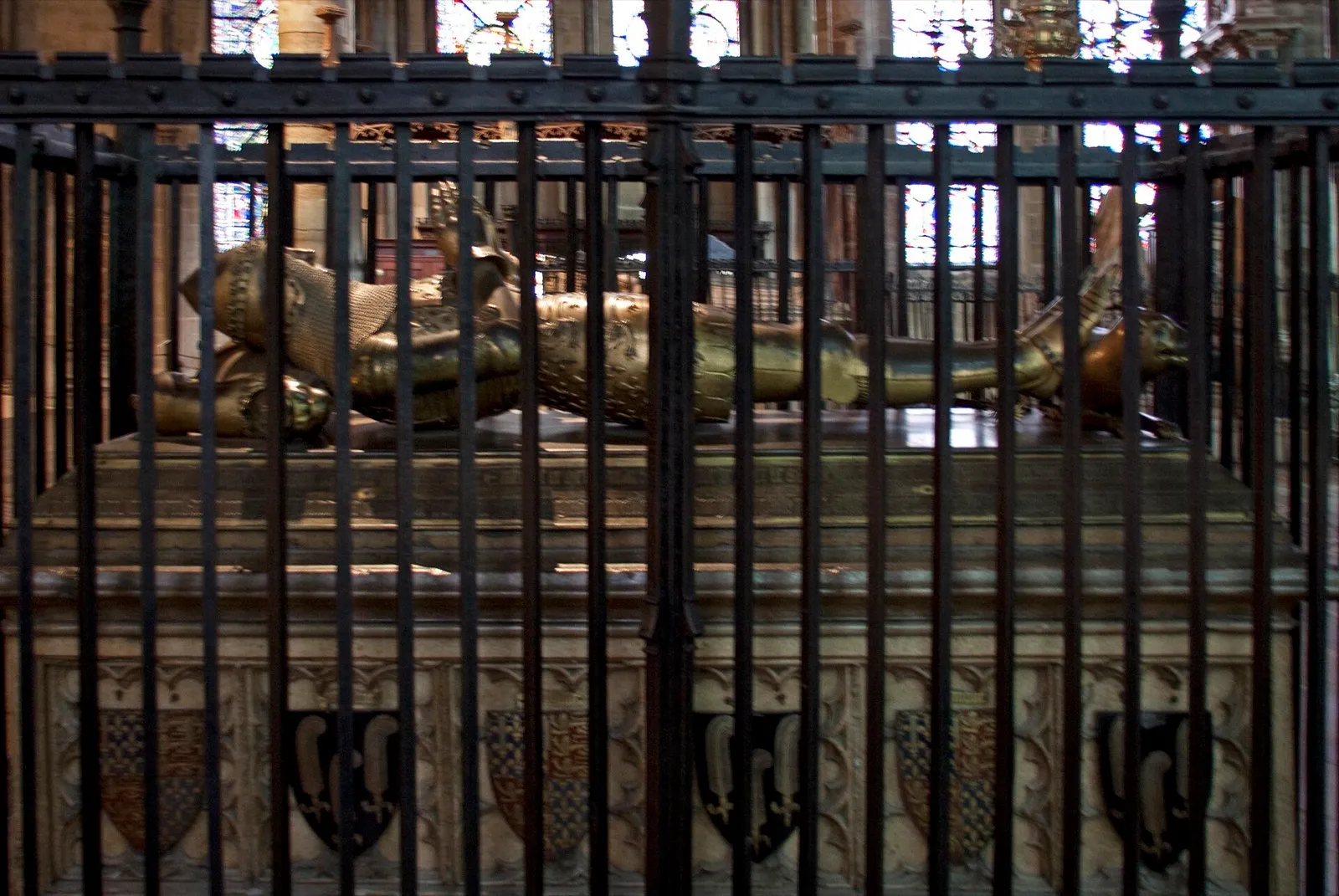 The gilt bronze effigy of the Black Prince lying on his tomb in Canterbury Cathedral, seen through iron railings