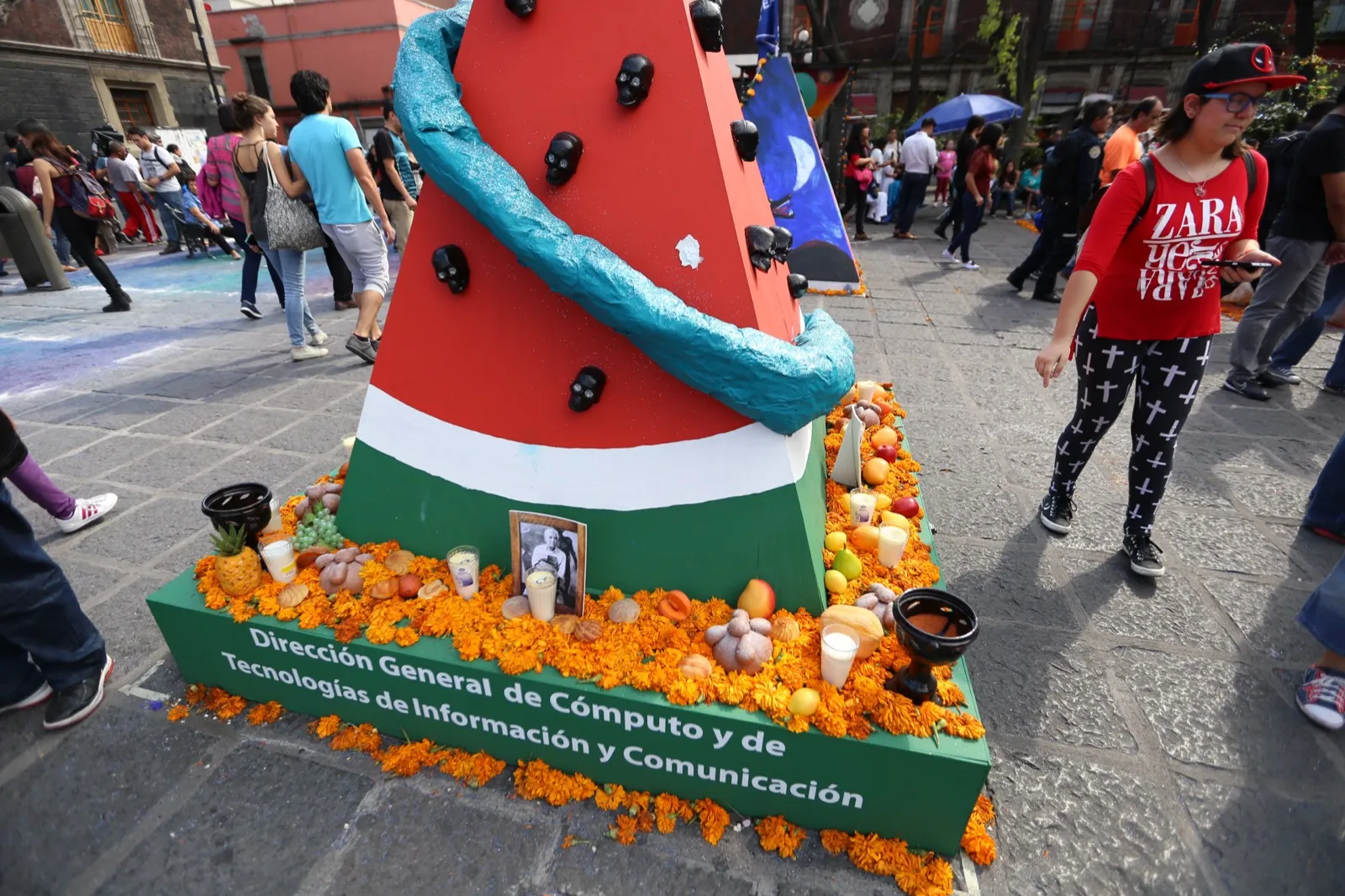 A Day of the Dead ofrenda in Mexico City, with a black-and-white photograph of an elderly man surrounded by orange marigolds, candles, bread and fruit