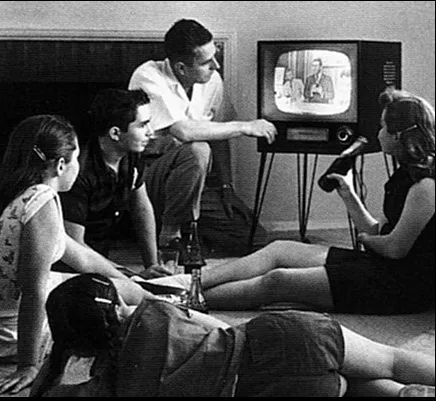 A family in the 1950s sitting on the floor watching a television set