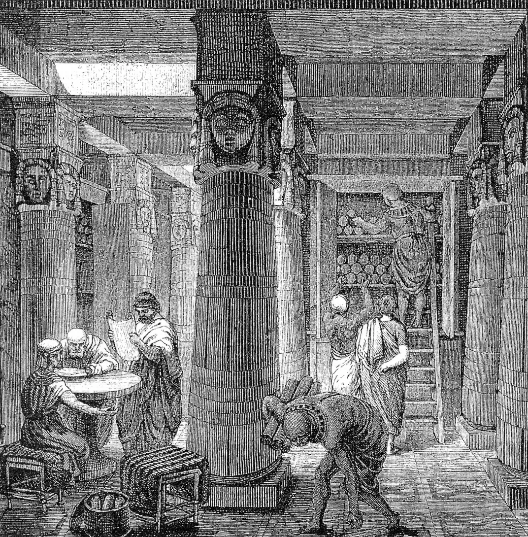 An engraving of the interior of the Library of Alexandria, with scholars reading scrolls at a table between huge Egyptian columns and shelves stacked with scrolls