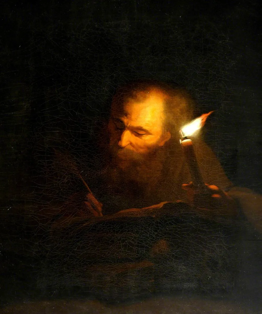 A bearded old man in dark robes bent over a book, writing with a quill by the light of a single candle