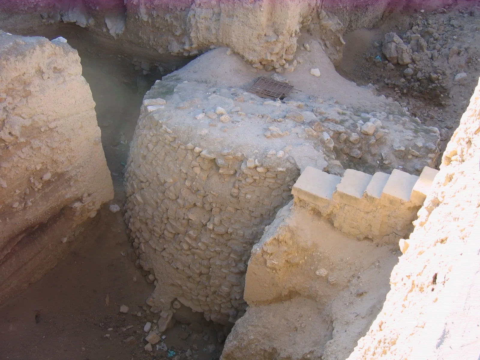 The excavated stone Tower of Jericho, a round tower of rough fieldstones standing in a deep archaeological trench at Tell es-Sultan